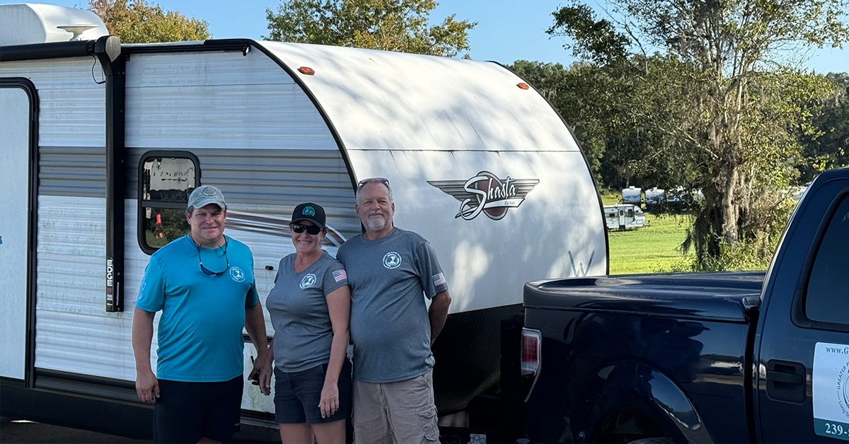 2 guys and lady standing in front of their trailer